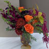Orange roses and burgundy flowers in a glass vase