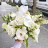 White rose and orchid bouquet held outdoors