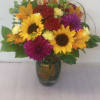 Bouquet of sunflowers, red roses, and purple mums in a glass vase