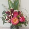 Pink roses and a peach dahlia in a glass vase with burgundy lilies