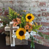 Sunflowers and white lilies arranged with a wooden cross