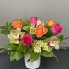 Pink and orange roses with orchids in a white vase