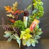 Autumn floral arrangement with an orchid, pinecones, and packaged candy bars in a vase.