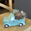 Succulents arranged in a turquoise ceramic truck planter