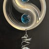 Metal wind chime with blue and clear crystal accents hanging on a dark surface