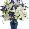 White lilies and blue irises in a blue glass vase
