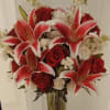 Red roses and white-red lilies in a clear glass vase