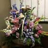 Basket arrangement with pink lilies, lavender roses, and blue flowers
