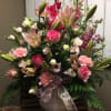 Pink and white floral arrangement in a white vase with a ribbon bow