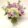 Pink roses and pastel hydrangeas arranged in a clear glass vase