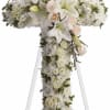 White floral cross on an easel with roses and lilies