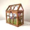 Wooden terrarium with purple orchids and succulents inside