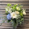 Mixed white and blue flowers arranged in a clear glass vase