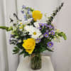 Bouquet of yellow roses, white daisies, and purple asters in a glass vase