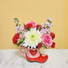 Pink and red flower arrangement in a heart-shaped mug and boot container