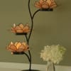 Three orange lotus-shaped candle holders on a black metal stand