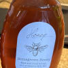 Bottle of honey with a white cap and labeled front