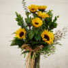 Bright sunflowers and variety of greens in a tall vase