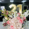 Pink and white floral arrangement with a gold "21" balloon