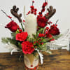 Holiday arrangement with red roses, carnations, and reindeer antlers in a decorative vase
