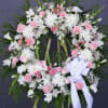 Pink and white floral standing wreath on an easel with a ribbon bow