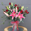 Bouquet of pink lilies and red roses in a glass vase with a pink ribbon