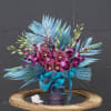 Bouquet of purple orchids and blue feathers in a decorative vase