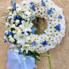 White daisy wreath with blue flowers and lilies on a stand