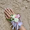 Pink and white wrist corsage with ribbon on a hand