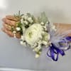 White ranunculus corsage with baby's breath and purple ribbon