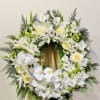 White floral wreath on a wooden easel with orchids and roses