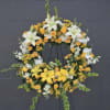 Circular floral wreath with white lilies, yellow roses, and white filler flowers