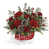 Red floral arrangement in a sleigh-shaped container with pinecones