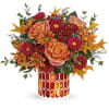 Orange and pink floral arrangement in a patterned vase