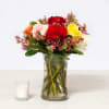 Mixed roses in a clear glass vase with a small candle beside it