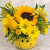 Yellow flower arrangement in a smiley-face container
