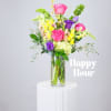 Mixed bouquet of pink, purple, and yellow flowers in a clear glass vase