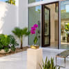 Purple orchid in a gold planter on a pedestal outside a modern home