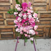 Pink and white floral standing arrangement on a purple easel