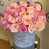 Round hat box of pink and peach roses arranged tightly together