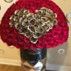 Large dome of red roses with a gold rose heart in a black hatbox on a tall pedestal.
