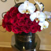 Red roses and white orchids arranged in a black hatbox