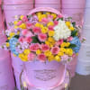 Pink hatbox arrangement of roses, hydrangeas, and lilac flowers