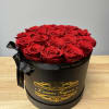 Round black hat box filled with tightly packed red roses