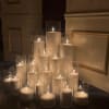 Cluster of lit white pillar candles in clear glass cylinders