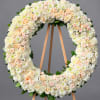 Large circular floral wreath of white and blush flowers on a wooden easel