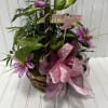 Basket arrangement with purple flowers, pink ribbon, and a "It's a Girl" pick