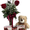Red roses in a vase with a teddy bear and chocolate box
