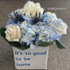 Blue and white floral arrangement in a white vase with text