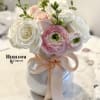 Pink and white roses with ranunculus in a white vase tied with a blush ribbon